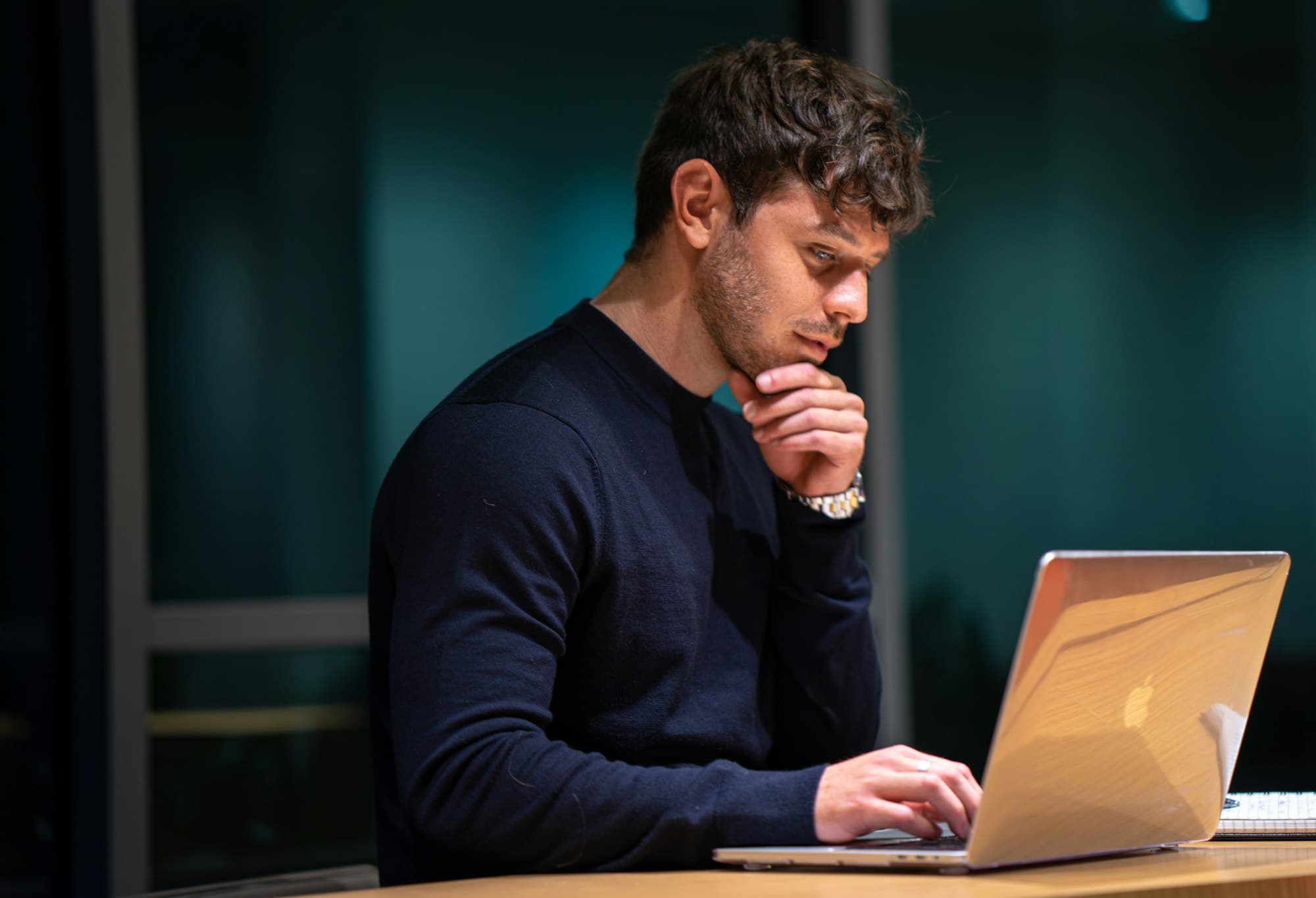 A technology buyer researching solutions on a laptop in a dimly lit office