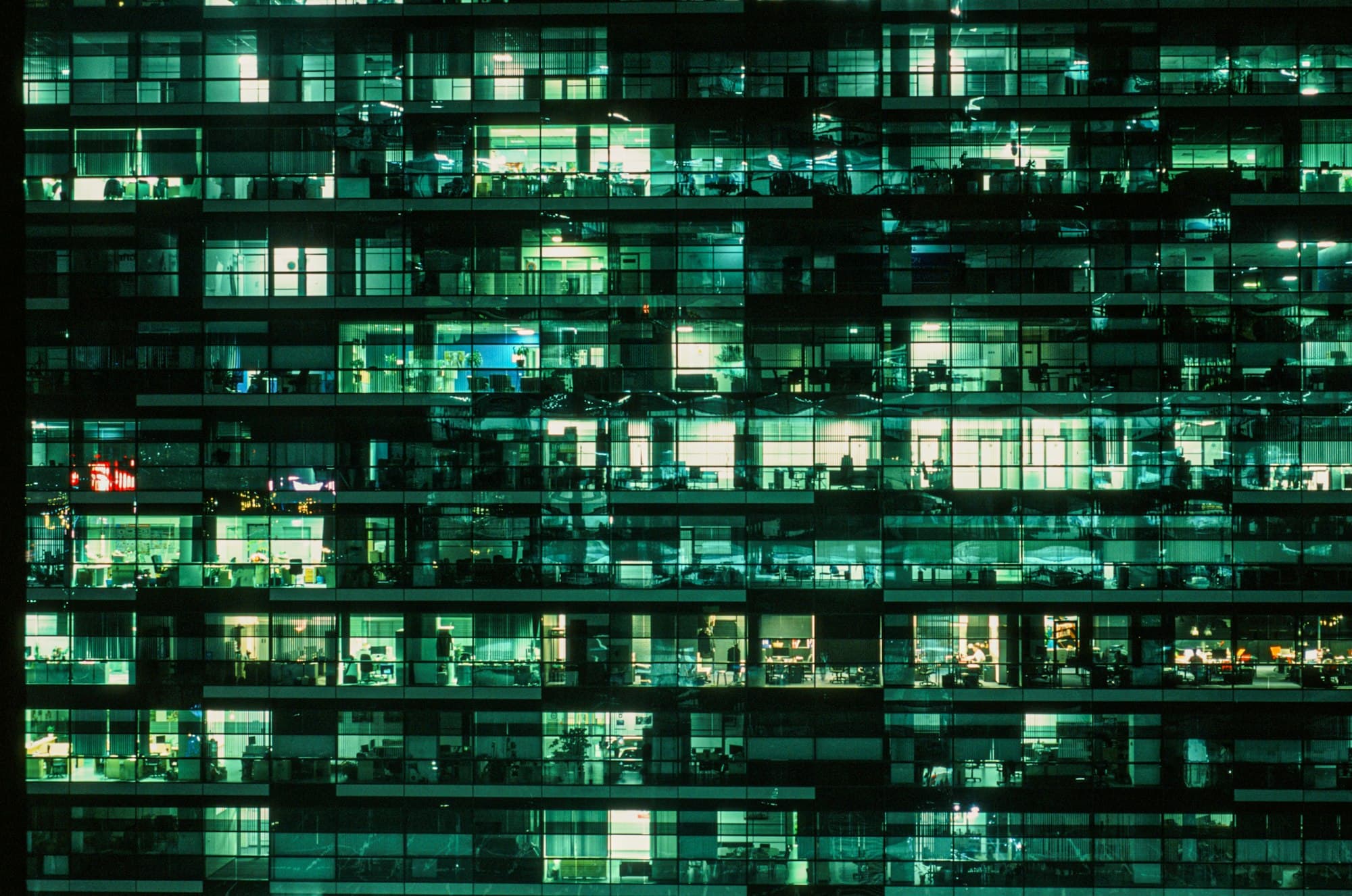 An office tower at night with lit windows across many floors