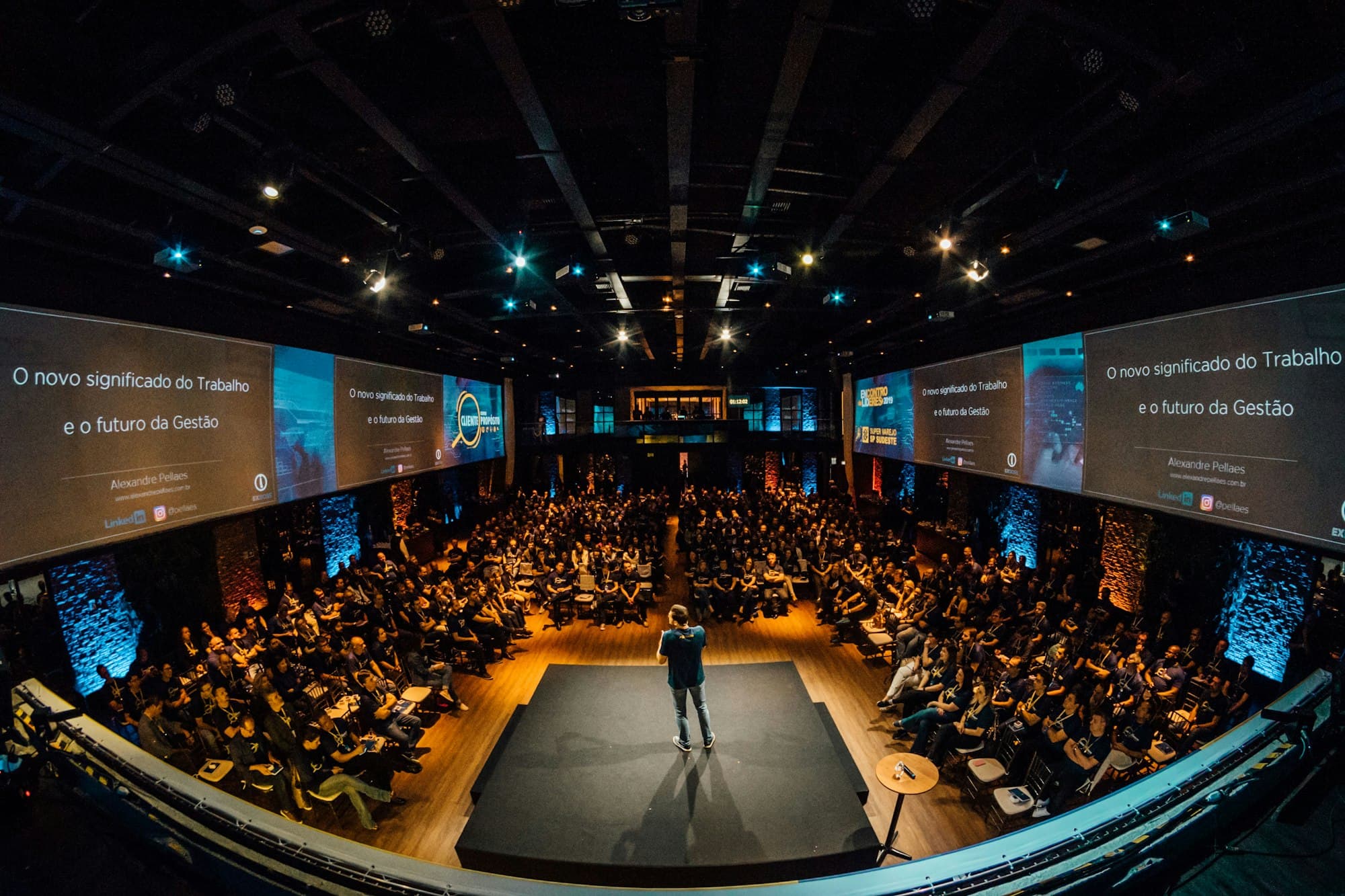 A large conference hall with an audience facing a speaker on stage